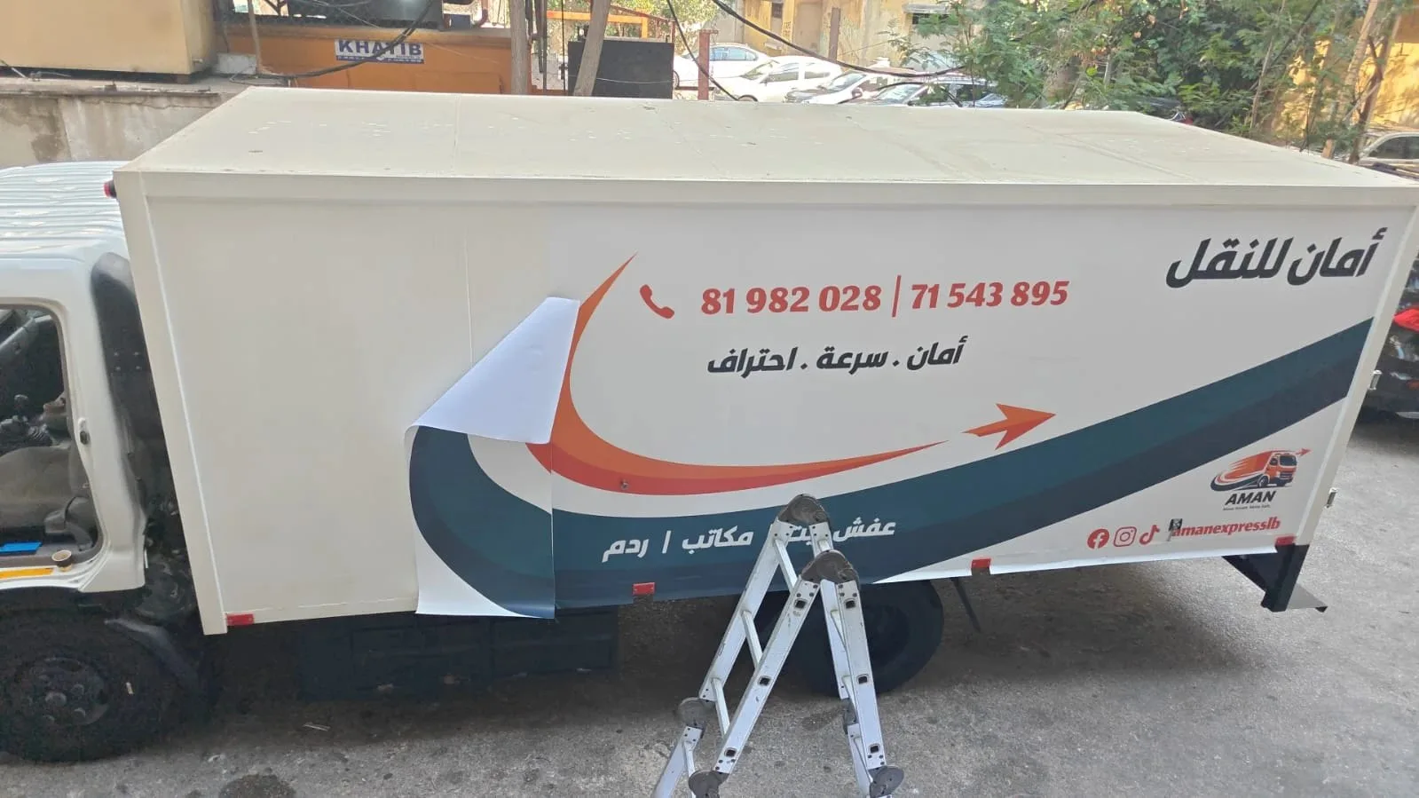 The printed vinyl being fitted on the truck side, one sheet still peeled back
