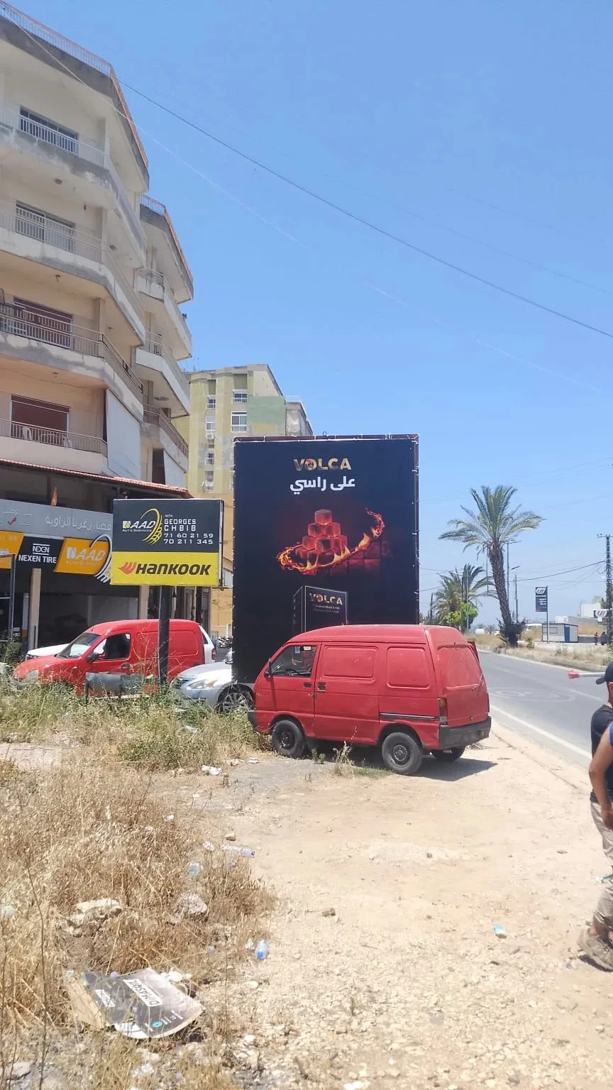 Volca portrait billboard next to a tyre shop, على راسي